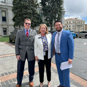 photo of two men and a woman in front of a statehouse